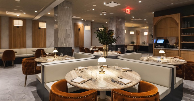 Interior, corner banquette benches with round marble top tables, ready for guests