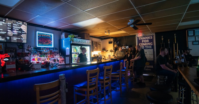 Bar, chairs, drink rack and tv screen behind