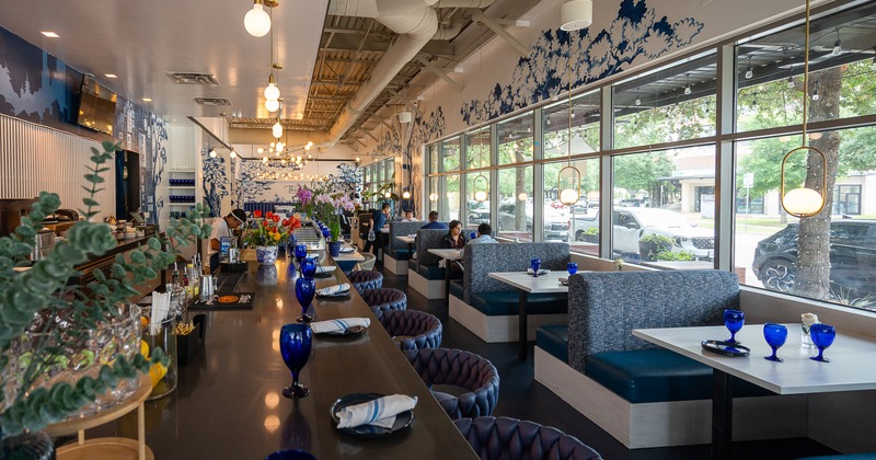 Spacious restaurant interior with dining booths along the windows and a bar counter set for guests