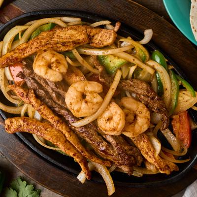 Top-down view of mixed fajitas with steak, chicken, and shrimp.
