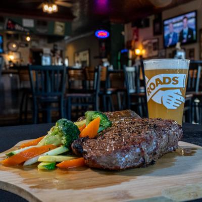 Grilled Ribeye with a side od vegetables served with a pint of beer.