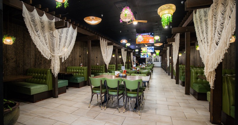 Interior, dining space with tables, chairs and dining booths, chandeliers and boho curtains