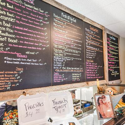 Chalkboard menu with handwritten daily specials displayed on small white counter.