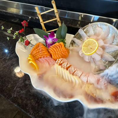 Platter with a dry ice mist display, featuring fresh salmon, whitefish and floral garnishes.