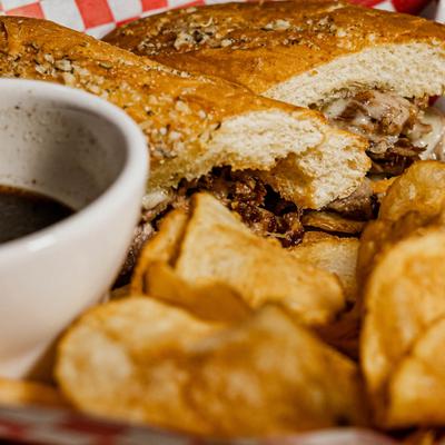 Roast beef sandwiches, with sauce and a side of potato chips