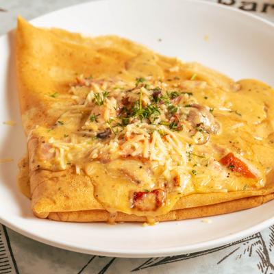 Savory crepe topped with sauce, grated cheese and herbs.