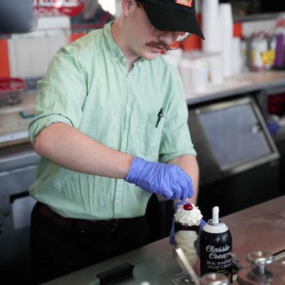 Interior, An employee preparing a dessert at a counter.