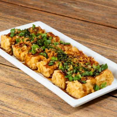 Fried tofu topped with herbs, green onion and sauce.