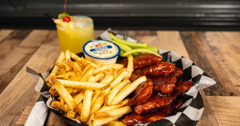 BBQ chicken fingers served with celery and fries, accompanied with Pineapple Margarita