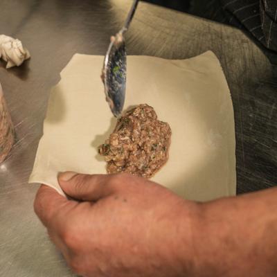 Preparation of Khinkali dumpling by placing raw minced meat on dough.