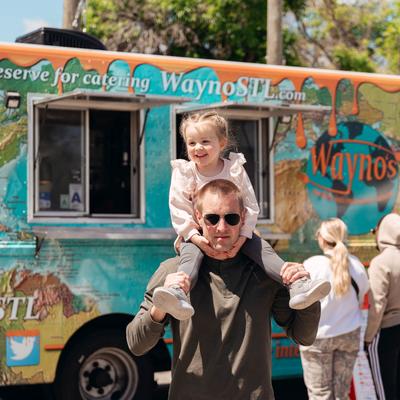 A person carrying a child, the food truck.