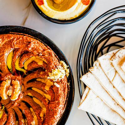 A dip of roasted peppers, pita, and hummus.