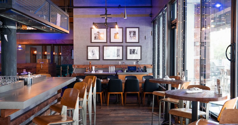 Interior, restaurant entrance, bar on the left, high tables with stools, shop window