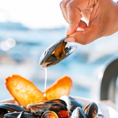 Hand holding a single mussel over the plate.