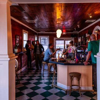 People chatting at a bar with checkered floor.