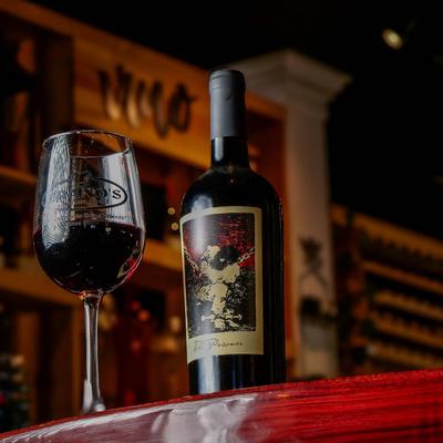 A glass of red wine standing next to a bottle of wine on a table, low angle view.