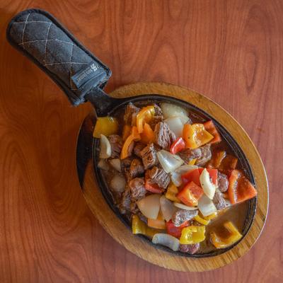 Beef stir-fry with bell peppers and onions in a cast iron skillet.