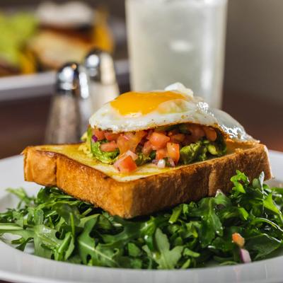 Avocado Texas Toast atop arugula, topped with pico de gallo and fried egg