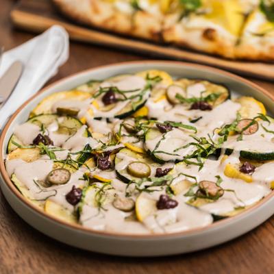 Pizza with grilled zucchini, canned tuna and anchovy sauce, capers, and olives.