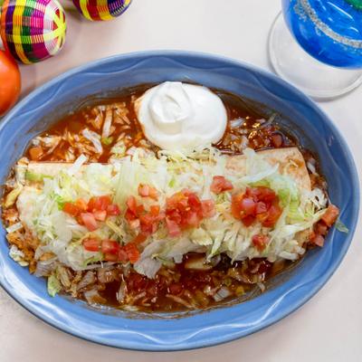 Burrito topped with shredded lettuce and diced tomatoes.