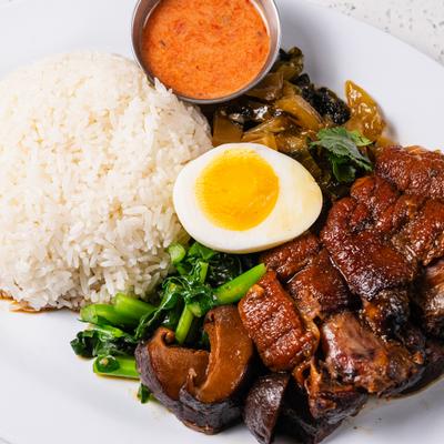 Thai style braised pork leg stew served with rice, a boiled egg and a dipping sauce.