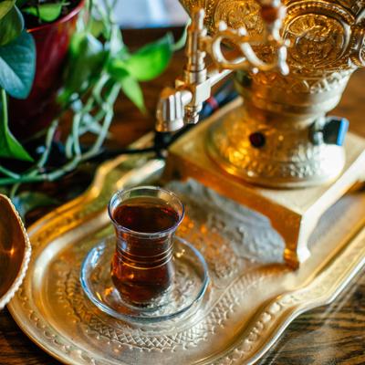A glass of tea and a golden teapot.