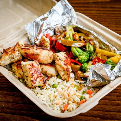 A bowl with chicken, rice, and vegetables.