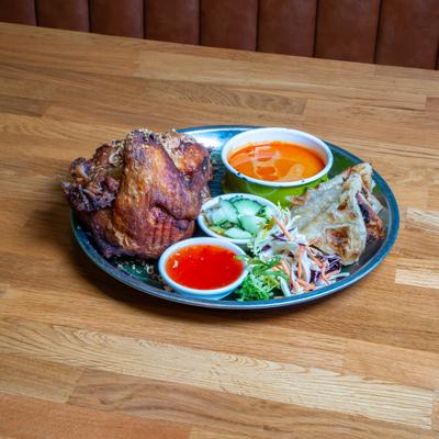 Crispy fried chicken with dipping sauces, cucumber salad, and coleslaw.