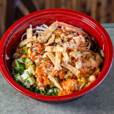 Poke bowl with shrimp, wonton strips, sauce, and cucumbers.