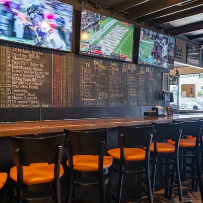 Interior featuring a counter, stools, chalkboard menu, and TVs displaying games.