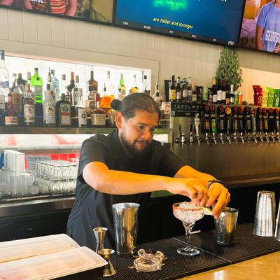 man behind bar making margarita.