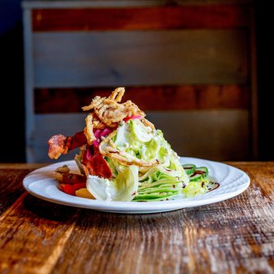 A plate holds wedge salad on a dining table.