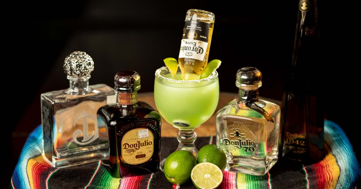 Tequila bottles and Corona Margarita cocktail arranged on a barrel with Mexican rug