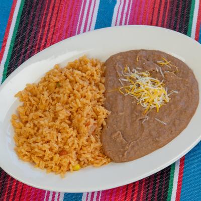 Seasoned rice and refired beans topped with cheese on a white plate.