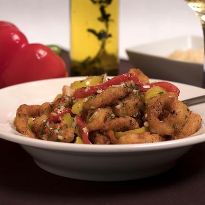 A plate of battered and fried shrimp garnished with peppers and herbs.