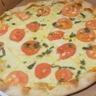 Margherita pizza with melted mozzarella cheese, fresh tomato slices, and basil.