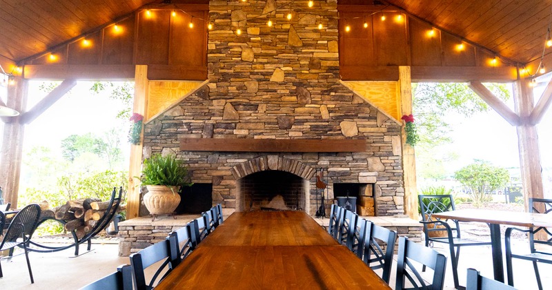 Exterior, outdoor covered seating area, long table setup. large stone brick fire place