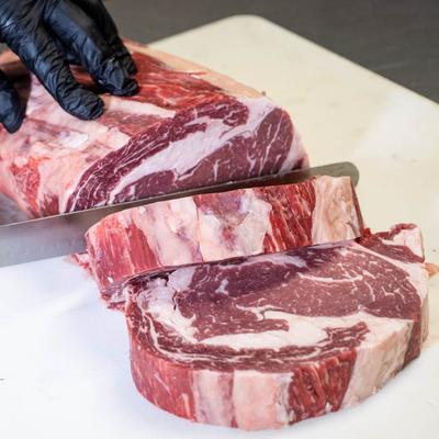 A hand slicing a large marbled piece of meat.