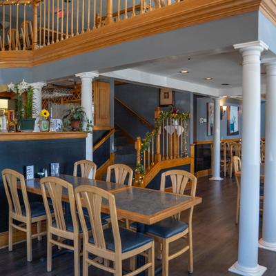 Interior of a restaurant with wooden furniture, white columns, and a decorated staircase.