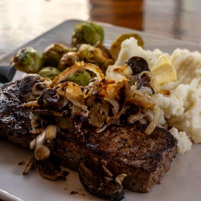 New York steak with mashed potatoes, brussels sprouts, and caramelized onions.