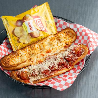 Meatball Sub served in a basket lined with checkered paper with a bag of chips.