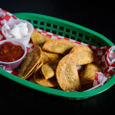Basket of crispy mini tacos with salsa and sour cream.