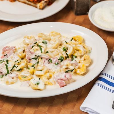 Cheese tortellini with ham and peas in cream sauce.