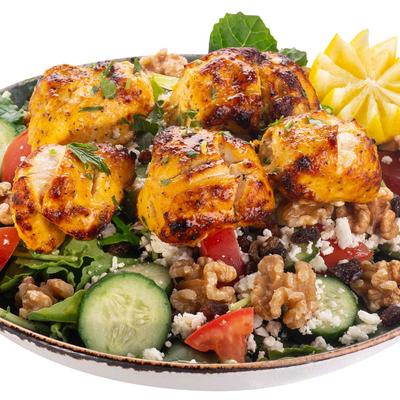 Chicken kebab salad with greens, cucumbers, walnuts, and cheese.