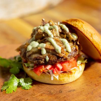 A burger topped with pulled pork and sauce.