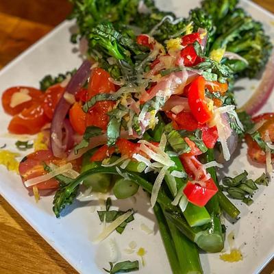 Broccolini starter dish with cherry tomatoes, red bell peppers, red onions and parmesan.