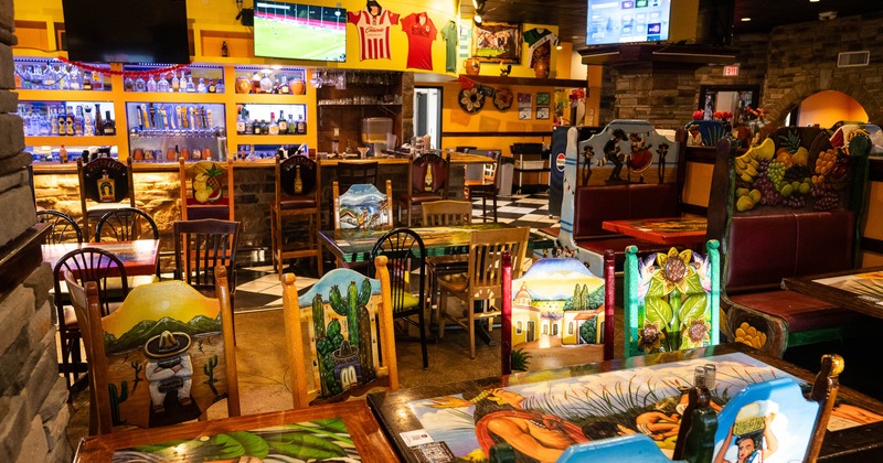 Colorful interior of Mexican restaurant with painted tables and chairs.