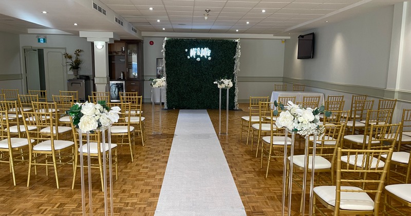 Wedding ceremony aisle and altar setup featuring a green boxwood backdrop and a white runner