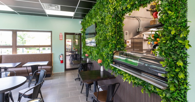 Interior of a dining area featuring green wall decor, black tables and chairs