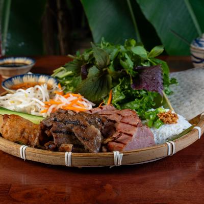 Tray of rice vermicelli noodles with grilled pork sausage, greens, and dipping sauce.